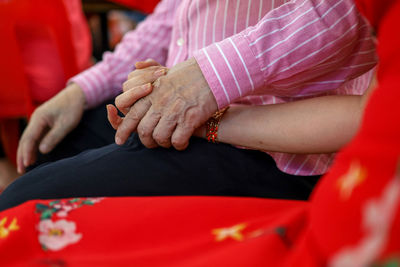 Midsection of couple holding red hands