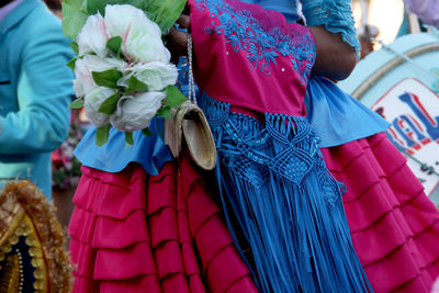 Mid section of a woman wearing holding purse and flower