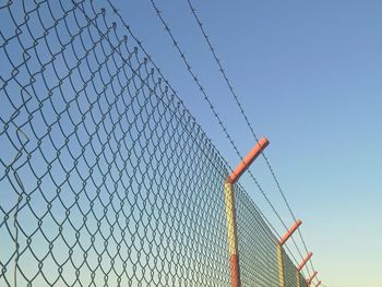 Low angle view of chainlink fence against clear blue sky
