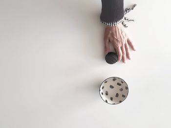 Cropped image of hand holding ball of wool by bowl on table