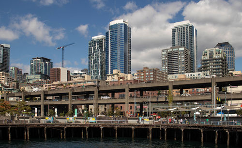 Modern buildings by river against sky in city