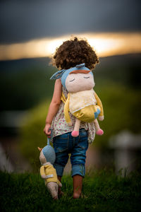 Rear view of girl with toys walking on field