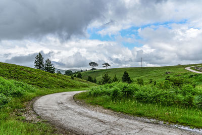 Road amidst field against sky