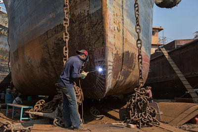 Side view of worker welding ship part at dry dock