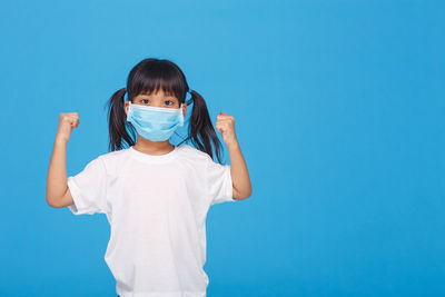 Portrait of girl standing against blue background