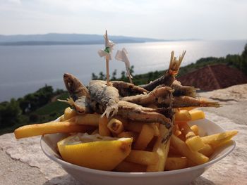 Close-up of fruits on table by sea against sky