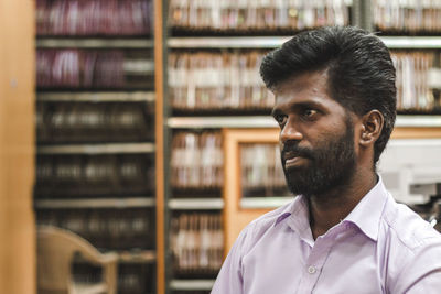 Man looking away against shelf