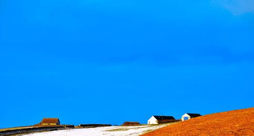 Houses on hill against blue sky