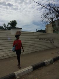 Full length rear view of girl standing against sky