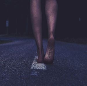 Low section of woman with neverland tattoo walking on road