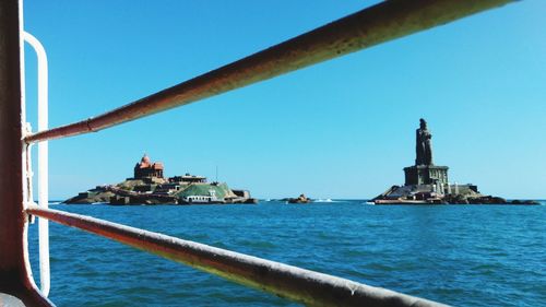 View of lighthouse by sea against clear sky