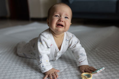 Portrait of cute baby girl on bed at home