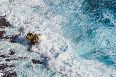 High angle view of wave splashing at rocky shore