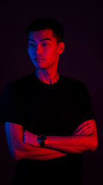 Portrait of young man standing against black background
