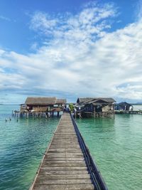 Scenic view of pier over clear turquoise sea against cloudy blue sky at natuna island, indonesia 
