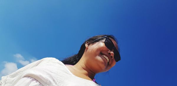 Low angle view of woman looking at blue sky