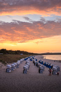 Chairs on beach against sky during sunset