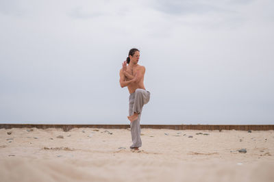 Full length of woman standing at beach against sky