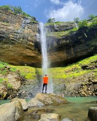 People standing on rock against waterfall