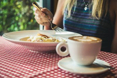 Close-up of woman holding tea cup on table