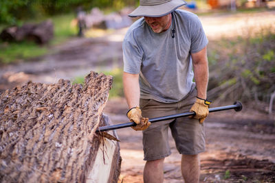 Full length of young man holding hat while standing on land
