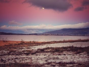 Scenic view of beach against sky at sunset