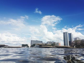 Modern cityscape by sea against sky