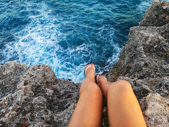 Low section of woman on rock in sea