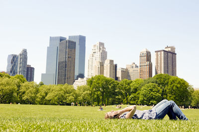 Woman in central park with manhattan skyline, new york city, usa