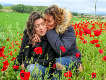 Women around poppy flowers on field