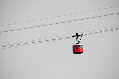 Low angle view of overhead cable car against sky