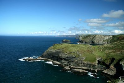 Scenic view of cliffed coast against blue sky