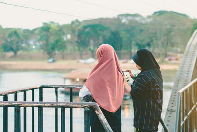 Rear view of couple standing against railing