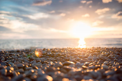 Surface level of pebble beach against sky during sunset