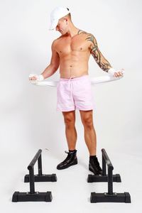 Full length of shirtless man standing against white background