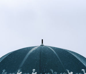 Low angle view of man with umbrella against clear sky