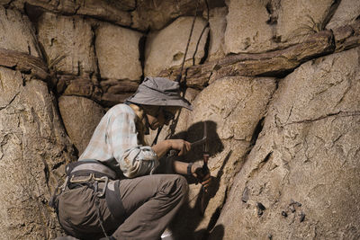 Side view of people sitting on rock