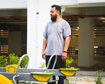 Mature man standing by seesaws at playground