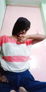 Young woman sitting on bed at home