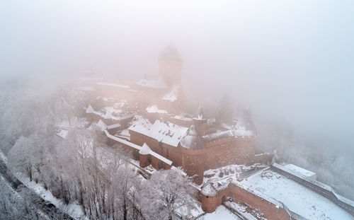 Aerial view of snow covered buildings against sky during winter