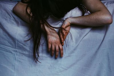 Cropped hand of woman gesturing on bed