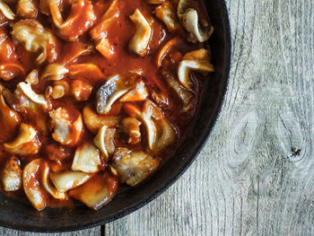 Directly above shot of pig ears in tomato sauce on wooden table