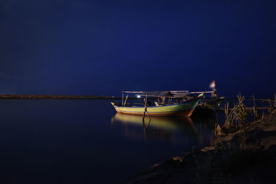Boats in sea against sky at night