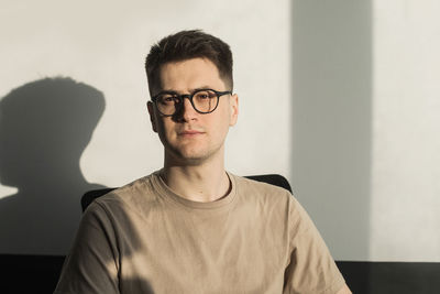 Portrait of young man standing against wall