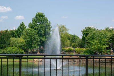 Fountain against trees and plants against sky