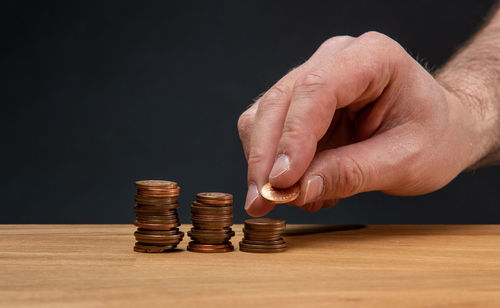 Close-up of hand on table against black background