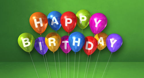 Close-up of multi colored balloons against green background