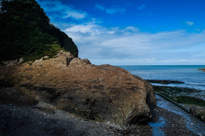 Scenic view of rocks on beach against sky