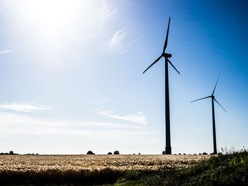 Wind turbines on field against sky