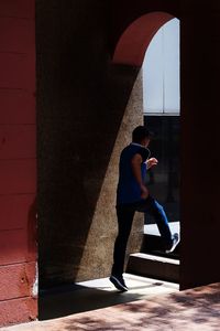 Side view of young man running on steps in building